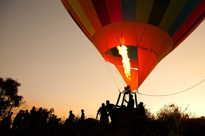 Soaring above Dubai witness the serene desert landscapes and the sun's warm embrace as you glide in a colorful hot air balloon creating memories against a breathtaking backdrop.